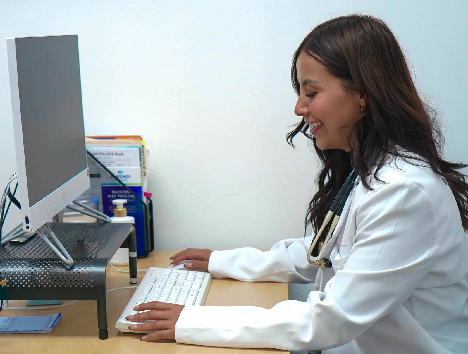 Una proveedora de Premier Clinic sonriendo en su escritorio durante una consulta.