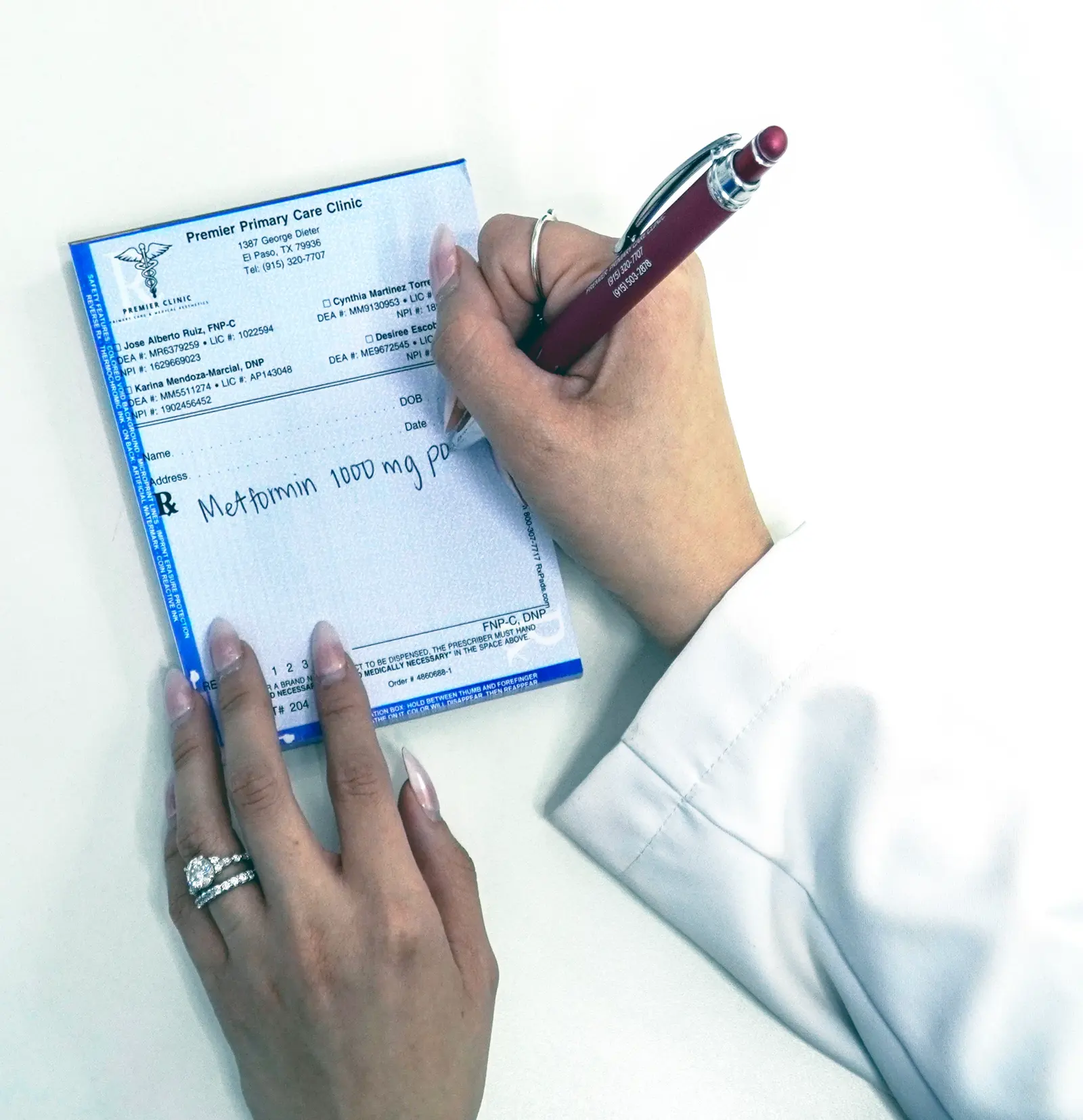 Manos escribiendo en un recetario de Premier Clinic