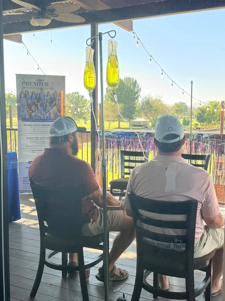 Dos clientes sentados junto al equipo de infusión y un letrero de Premier en una terraza